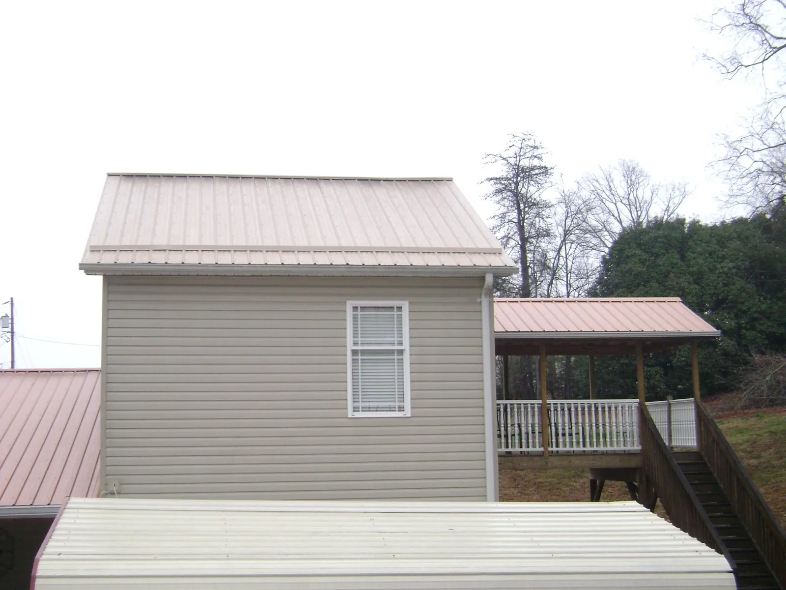 Tan metal roofs on a two story addition and attached porch, from a Roof Replacement job in Cragsmoor