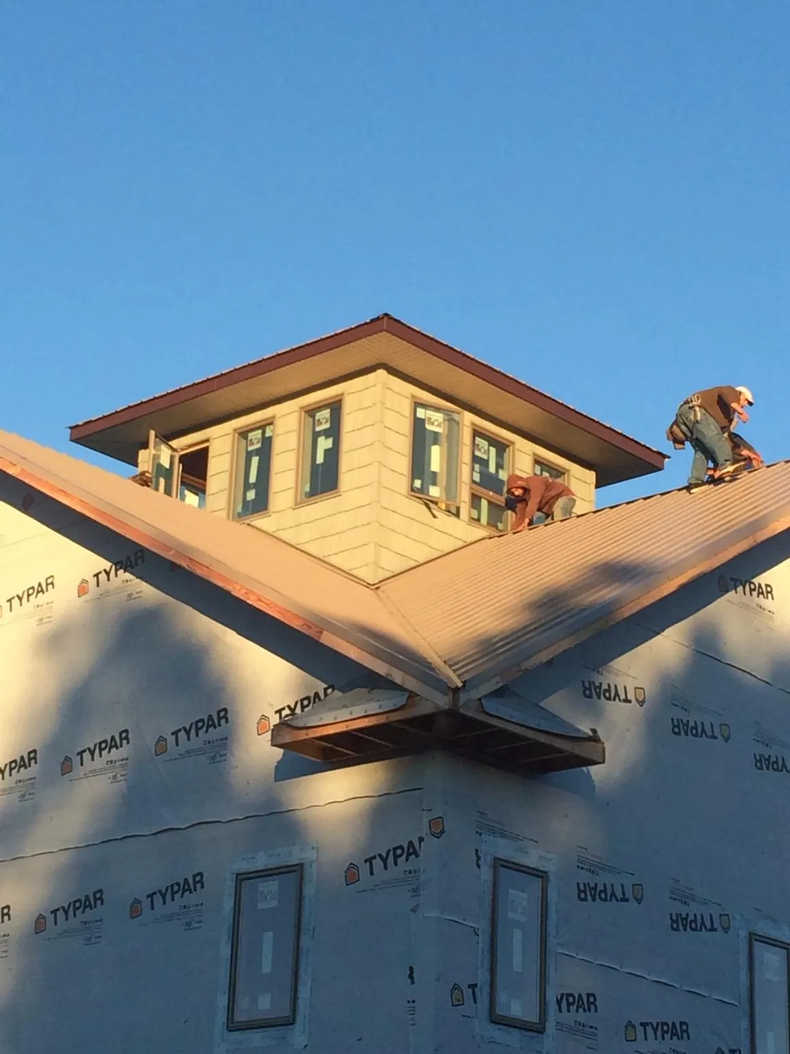 Roofers working around a rooftop cupola on a new metal roof at sunset — Roof Waterproofing in Cragsmoor by Roofing Brothers